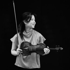 Hana Chang holding violin, in black and white